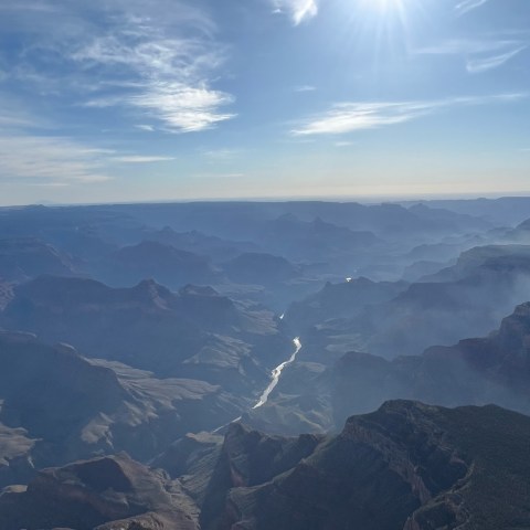 a plane flying high in the air with a mountain in the background