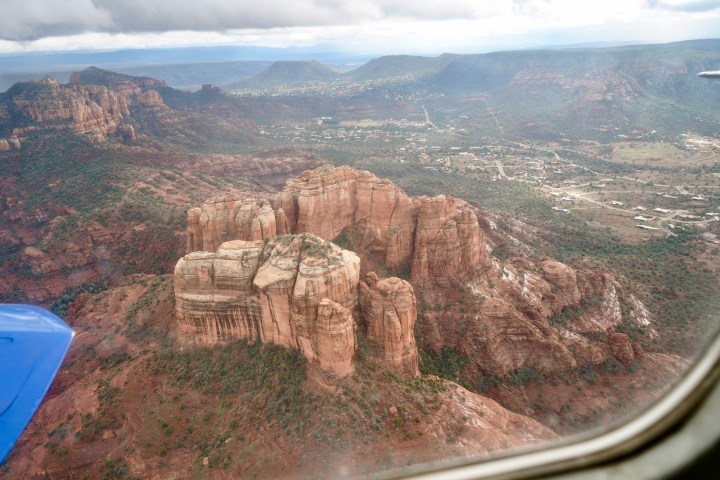 Aerial view of Sedona's red rock formations and valleys under a cloudy sky.