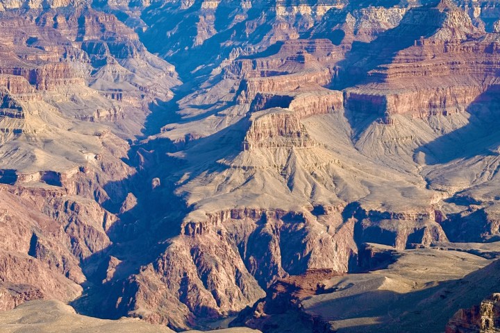 Grand Canyon landscape with deep valleys and layered rock formations under a clear sky.