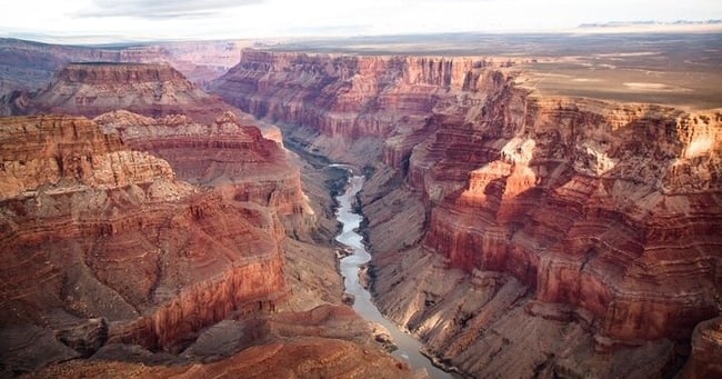 Aerial view of the Grand Canyon with a river flowing between red rock cliffs.