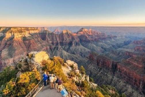 People at a viewpoint overlooking the Grand Canyon during sunset.