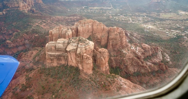 Aerial view of red rock formations and desert landscape from airplane window.
